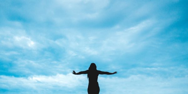 silhouette photography of woman raising her hands
