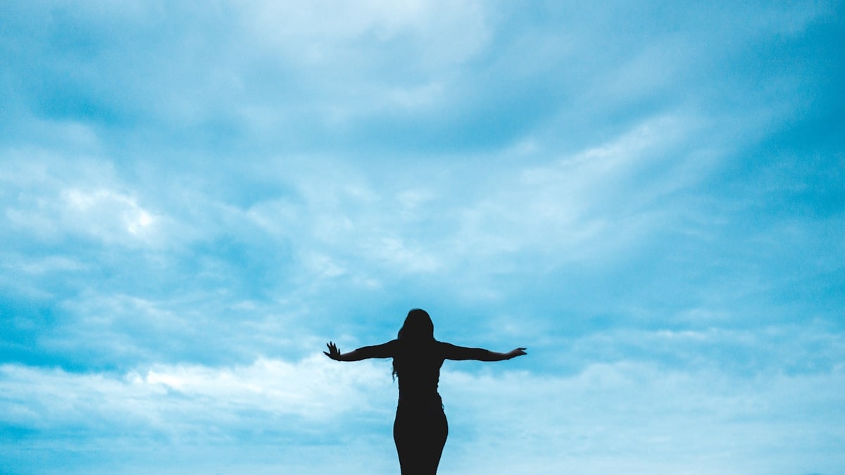 silhouette photography of woman raising her hands